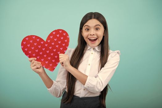 Cheerful lovely romantic teen girl hold red heart symbol of love for valentines day isolated on blue background