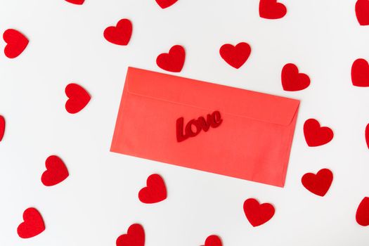 A love letter, the inscription of love on a red paper envelope on the background of small red hearts. The concept of St. Valentine's Day