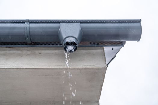 gutter with flowing rainwater on the roof of the building.