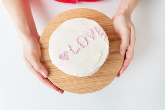 The girl is holding a Bento cake with the inscription Love and hearts. A small Korean cake for one person. A cute dessert gift for a loved one for any holiday. Valentine's Day