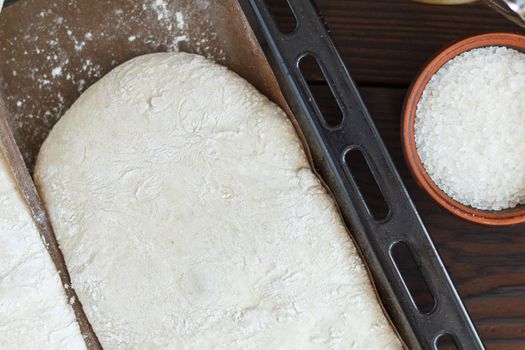 fresh raw dough for baking bread on a baking sheet, ready for baking on a wooden background. Close-up