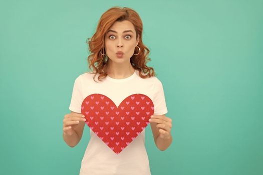 funny redhead woman hold red heart on blue background.