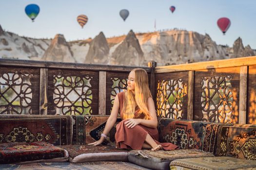 Tourist woman looking at hot air balloons in Cappadocia, Turkey. Happy Travel in Turkey concept. Woman on a mountain top enjoying wonderful view.