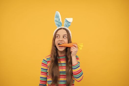 amazed easter teen girl in rabbit bunny ears eating carrot for holiday, easter holiday.