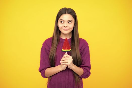 Teen girl hold lollipop caramel on yellow background, candy shop. Teenager with sweets suckers