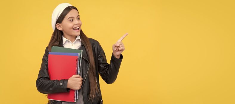 Look. Happy school child point finger yellow background. Portrait of schoolgirl student, studio banner header. School child face, copyspace