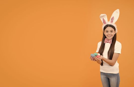 happy easter kid girl in bunny ears and bow tie hold painted eggs, copy space, easter.