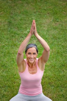 Yoga calms her. Portrait of an attractive mature woman doing yoga outdoors
