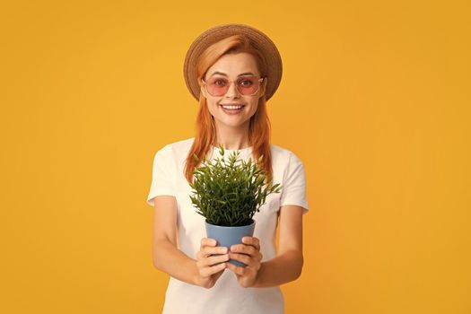 Portrait of gorgeous girl holds pots with exotic sprout. Beautiful lady in gardening outfit smiling. Pretty model working, summer gardening concept. Woman planting flowers in pot