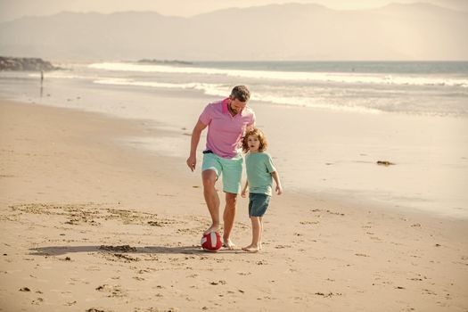 cheerful kid and dad running on beach in summer vacation with ball, friendship.