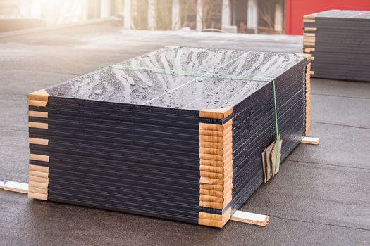 Green energy. Modules of solar panels for the production of renewable energy, lie on the roof of the building before installation, installation of solar panels