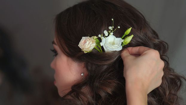 The stylist adorns the girl's hair with delicate flowers