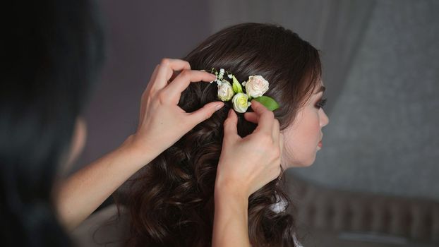The stylist adorns the girl's hair with delicate flowers