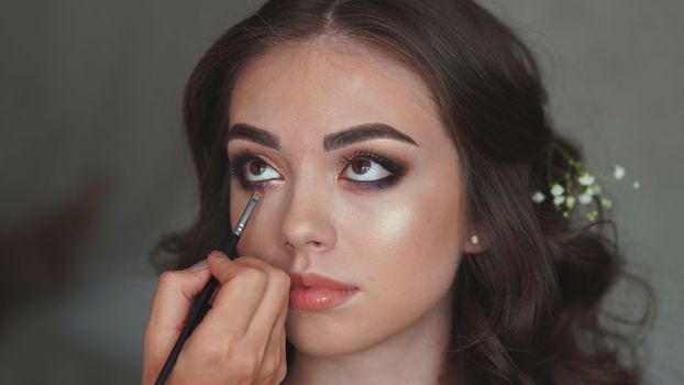 Makeup artist paints an eye for a model girl