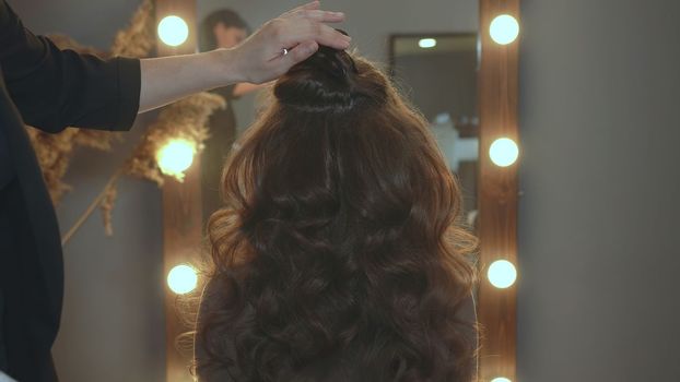 The hairdresser fixes curly hair with hairspray