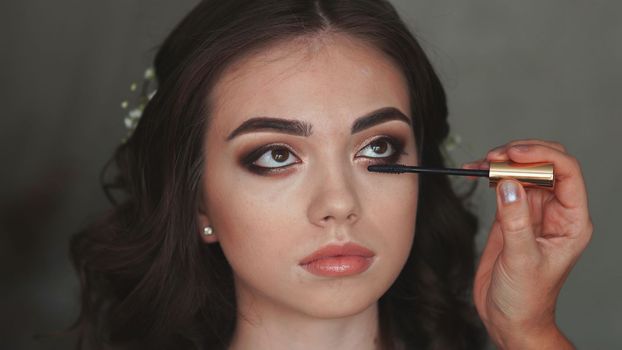 Girl makeup artist paints eyelashes on the model