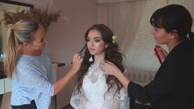Makeup artist and hairdresser work on the image of the model