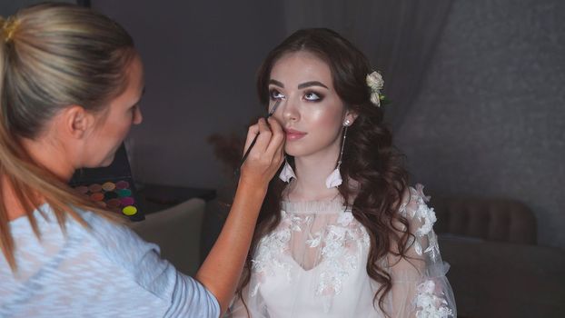 Makeup artist paints an eye for the bride on her wedding day