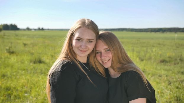 Portrait of two twin sisters in the field on a warm summer day.