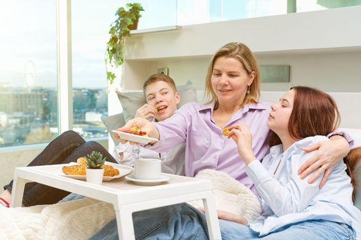 Mother having breakfast in bed with her childrens at mothers day. family breakfast in bedroom. Happy mother with her little daughter and son having breakfast together in bed at home.