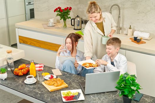 Young family with school kids have fun at breakfast time. Happy family eating healthy breakfast. Quality time with Family in kitchen eating together. Family Using Digital Devices At Breakfast