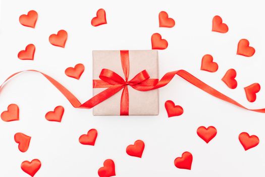 Hearts gift box with a red bow on a white background with red hearts. Festive web banner. View from above