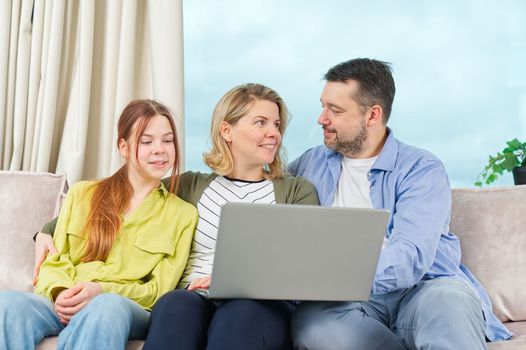 Happy Family on couch using gadget. Watching something online on computer together with family. Rest at home.