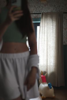 Beautiful woman in white silk pyjama standing near window in a cozy room. emotional portrait.