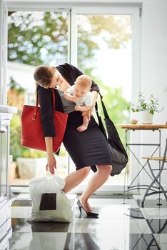 Ill check my diary and get back to you. a busy businesswoman carrying a shopping bag and her baby while talking on the phone on her return from work