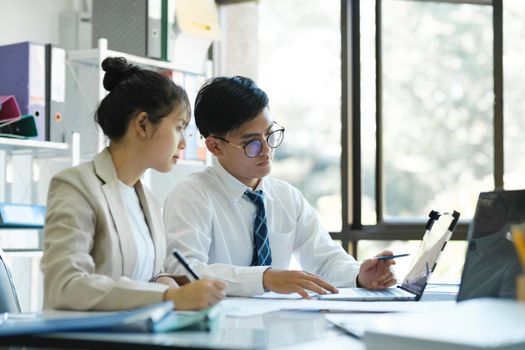 Businesspeople or colleagues are working together on investment project, discussing, sharing ideas, planning, and analyzing the business strategy and finance using laptop and graphs at workplace.