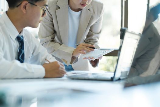 close up businesspeople or office workers are working together on investment project. They are discussing, sharing the ideas, planning, and analyzing the business strategy. And set up the budget for financial plan by using laptop and calculator.