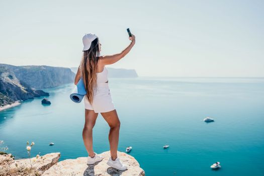Young woman with black hair, fitness instructor in pink sports leggings and tops, doing pilates on yoga mat with magic pilates ring by the sea on the beach. Female fitness daily yoga concept