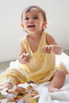 Fun with blocks. an adorable baby girl sitting on the floor playing with toys