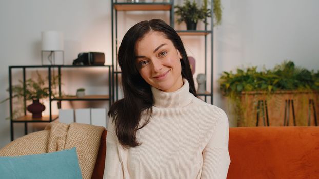 Portrait of happy calm brunette woman at home couch smiling friendly, glad expression looking away dreaming resting, relaxation feel satisfied concept good news, celebrate win. Girl in living room