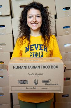 Portrait of Ukrainian volunteer woman with paper box of humanitarian aid. Dnipro, Ukraine - 06.28.2022