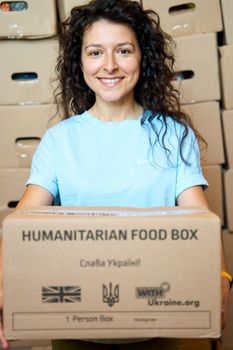 Portrait of Ukrainian volunteer woman with paper box of humanitarian aid. Dnipro, Ukraine - 06.28.2022