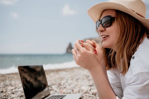 Woman sea laptop. Business woman in yellow hat working on laptop by sea. Close up on hands of pretty lady typing on computer outdoors summer day. Freelance, digital nomad, travel and holidays concept