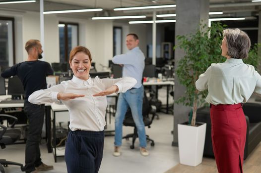 Four office workers warm up during a break. Employees do fitness exercises at the workplace