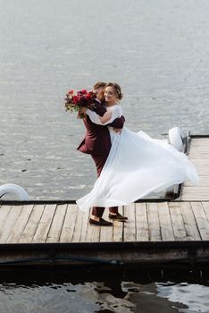 the first meeting of the bride and groom in wedding dresses on the pier near the water