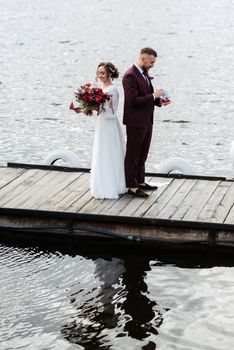 the first meeting of the bride and groom in wedding dresses on the pier near the water