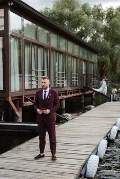 the first meeting of the bride and groom in wedding dresses on the pier near the water