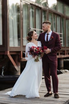 the first meeting of the bride and groom in wedding dresses on the pier near the water