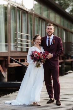 the first meeting of the bride and groom in wedding dresses on the pier near the water