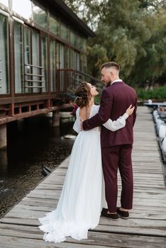 the first meeting of the bride and groom in wedding dresses on the pier near the water