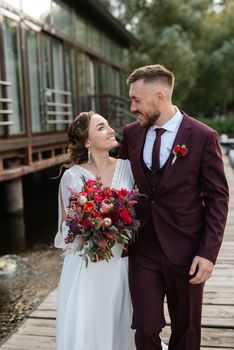 the first meeting of the bride and groom in wedding dresses on the pier near the water