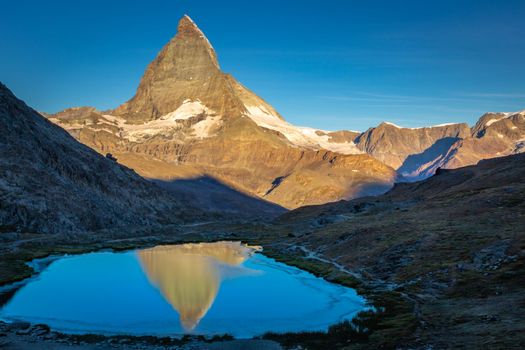 Reflection of the Matterhorn on blue and placid lake at sunrise, Swiss Alps, Zermatt, Switzerland