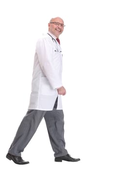 Mature doctor with stethoscope walking on white background, side view