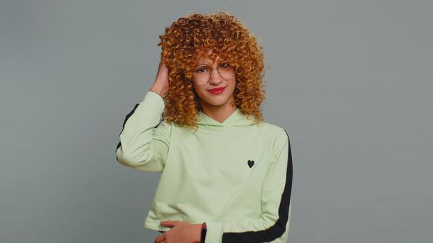 I dont know what to say. Confused young teenager school girl feeling embarrassed about ambiguous question having doubts no idea, being clueless and uncertain. Curly hair child kid on gray background