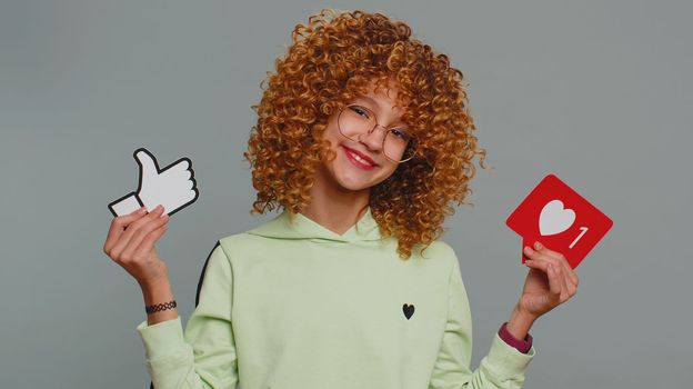 Like. Happy young child girl kid looking approvingly at camera showing thumbs up, like sign banner social media logo, something good, positive feedback. Teenager children isolated on gray background