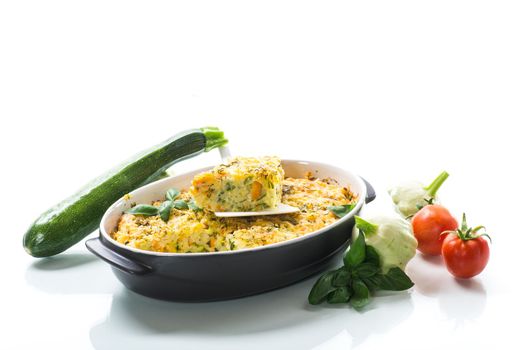 vegetable casserole of patissons, zucchini, carrots in a ceramic form isolated on a white background